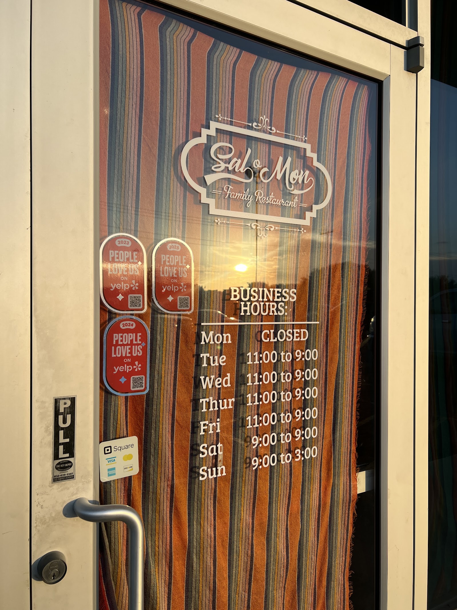 Front door of Sal-O-Mon Family Restaurant with logo and posted business hours